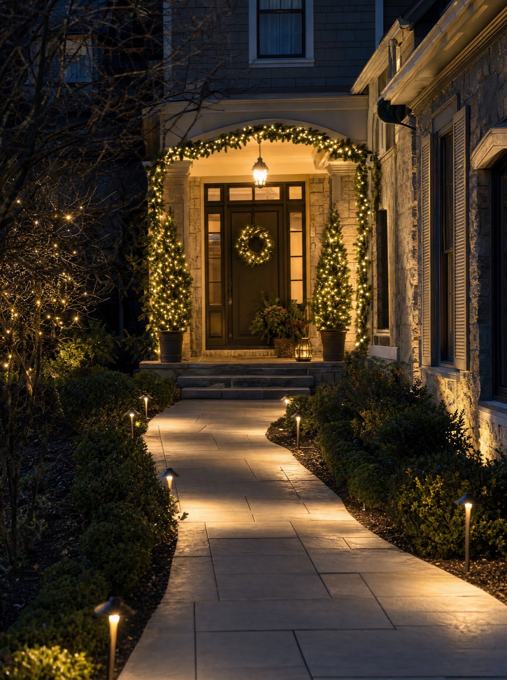 Stone walkway lined with path lights leading to a lit front entry