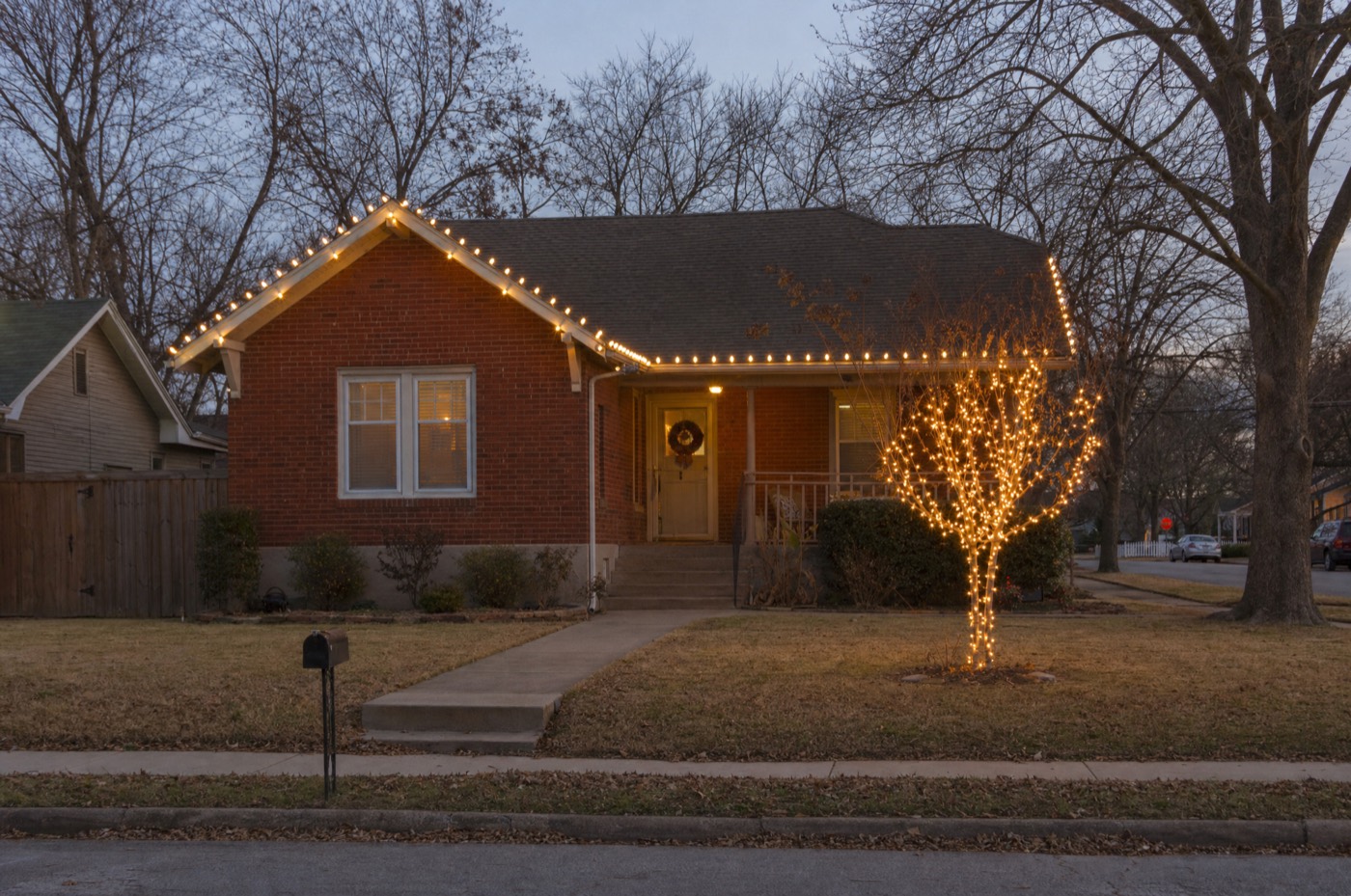 Small brick bungalow with warm white roofline and a wrapped crepe myrtle